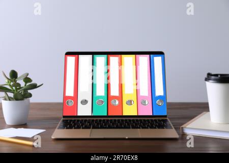 Store and organize information. Modern laptop with hardcover office folders on screen Stock Photo