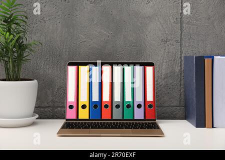 Store and organize information. Modern laptop with hardcover office folders on screen Stock Photo