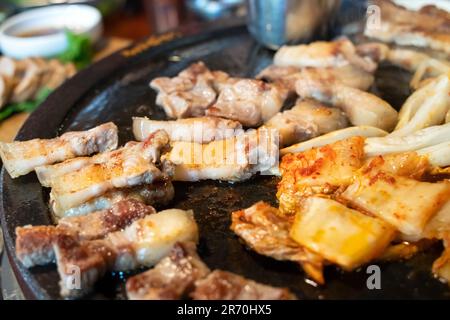 Pan-fried black pork meal in Jeju Korean restaurant, fresh delicious korean food cuisine on iron plate with lettuce, kimchi, banchan and sauce, lifest Stock Photo