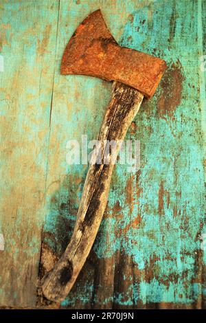 Old rusty ax lies on the blue shabby table Stock Photo