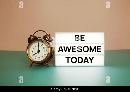 Be Awesome Today text message on paper card with wooden easel and alarm clock Stock Photo