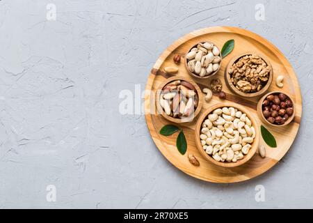 mixed nuts in wooden bowl. Mix of various nuts on colored background. pistachios, cashews, walnuts, hazelnuts, peanuts and brazil nuts. Stock Photo