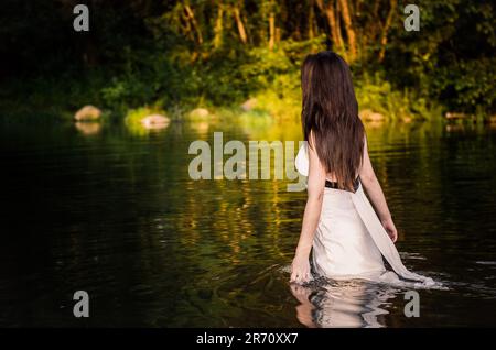 A young female standing in a shallow body of water. Stock Photo