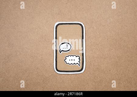 Mobile phone made our of paper with bot in the speech bubble on the display, concept of chatting with bot, chat gpt. Asking question to AI. Cardboard Stock Photo