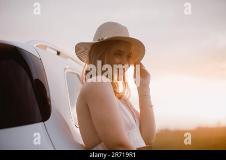 Portrait of young smiling woman standing near her car, enjoying summer time. Stock Photo