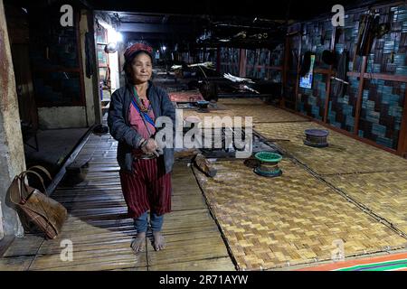 Local woman from a Nyishi tribe standing in a traditional long house made from bamboo in arunachal pradesh in northeastern part of India, Stock Photo