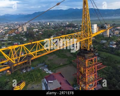 Close-up view from a drone of a construction crane cabin against the backdrop of beautiful mountains. Construction concept Stock Photo