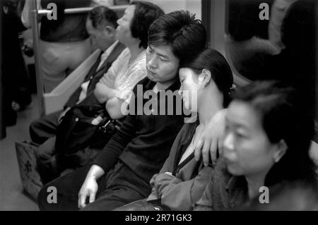 Tired people, a couple, the young woman is asleep on her partners shoulder on a tube train. Passengers going home at the end of the days work. The metro in Shanghai China 2000 2000s HOMER SYKES Stock Photo