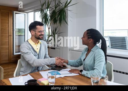 Young architect consulting project with client. Interior designer architecture expert making a deal with handshake after successful project and satisf Stock Photo