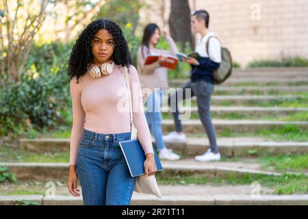 Black teenager with curly hair is looking at camera with a serious face Stock Photo