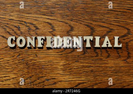 Confidential, word in wooden alphabet letters isolated on textured wood background Stock Photo