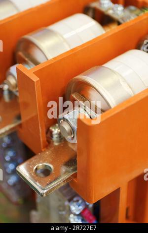 Part of high voltage electrical installation, big fuses installed inside an orange protective housing, vertical close-up shot with selective focus, in Stock Photo