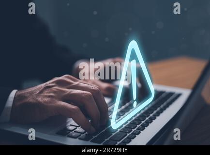 Error and maintenance alert. Businessman using computer laptop with triangle caution warning sing for notification error and maintenance concept. Stock Photo