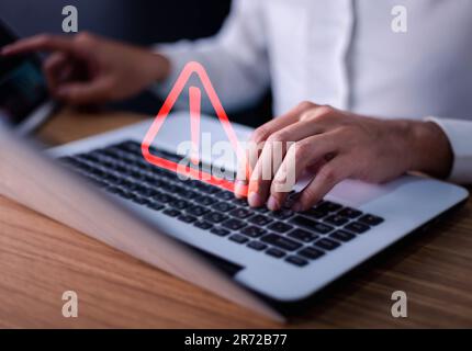 Error and maintenance concept. Businessman or it staff , programmer, developer using computer laptop with triangle caution warning sign for notificati Stock Photo