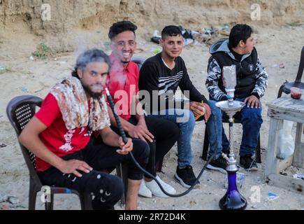 Gaza, Palestine. 11th June, 2023. Palestinian youths smoke shisha on the beach in Deir El Balah, central Gaza Strip. Credit: SOPA Images Limited/Alamy Live News Stock Photo