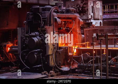 Rolled metal factory hot steel bar on conveyor moving through rollers. Stock Photo