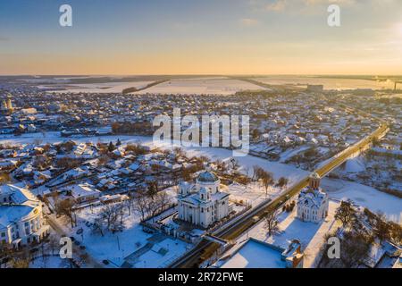 Nice top view of the winter city. Houses and buildings in the snow. Bridge over river. Orthodox churches and a Catholic cathedral. The river is covere Stock Photo