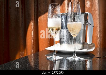The two glasses with sparkling champagne with a bucket of ice in the background Stock Photo