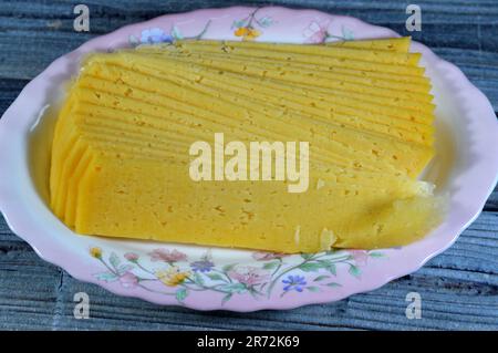 Slices of Egyptian Rumi cheese, also called gebna romiya or gebna turkiya, Roumi, Romi also Romy, middle Eastern parmesan hard cheese, has a pungent s Stock Photo