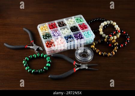 Beads and tools for jewellery making on a polished wooden surface Stock Photo