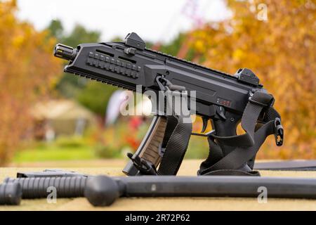 Modern submachine gun with black belt on autumn background Stock Photo