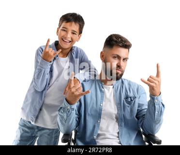 Little boy and his father in wheelchair showing 'devil horns' gesture on white background Stock Photo