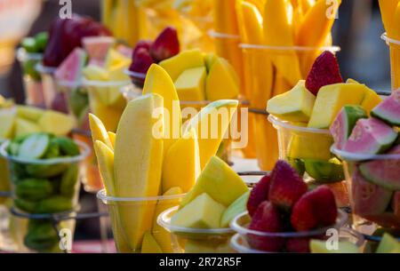 Closeup of chopped colourful fresh tropical fruits in cups for sale at Vietnam local street market. Stock Photo