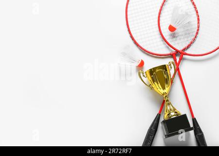 Gold cup with badminton rackets and shuttlecocks on light background Stock Photo
