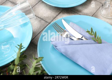 Plates with folded napkin, cutlery and glass on grey tile background Stock Photo