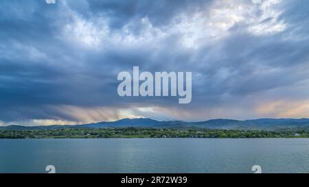 dramatic storm clouds at dusk over Rocky Mountains and lake in northern Colorado Stock Photo