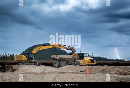 Excavator and dumper at work on a construction site with stormy sky Stock Photo