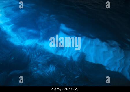 Blurred blue underwater view with white sand on a seabed and deep blue rocks. Abstract natural background photo Stock Photo