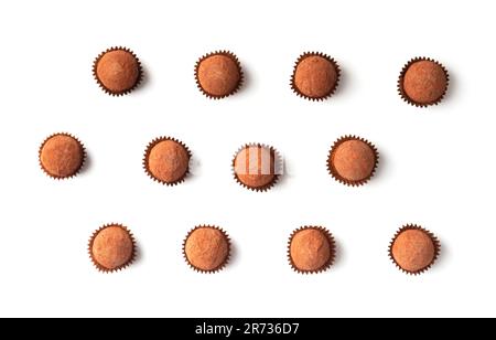 A lot of chocolate truffles in individual paper packages on a white background, top view. Round handmade sweets sprinkled with cocoa powder Stock Photo