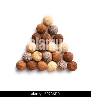 Round sweets truffles made of milk, black and white chocolate stacked in the shape of a triangle on white isolation top view. Mix of sweet truffles Stock Photo