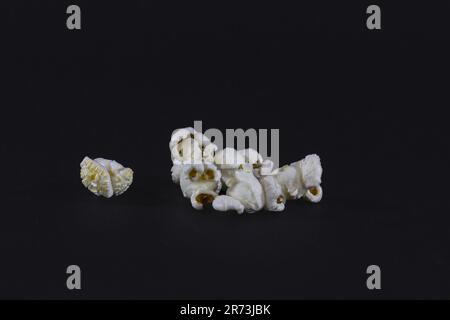 Picture of isolated white popcorn on black background. Popcorn is a variety of corn kernel which expands and puffs up when heated; the same names also Stock Photo
