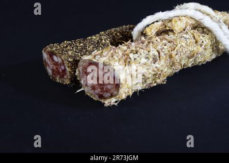 Picture of a fuet sausage sliced and coated in peppercorn. Fuet is a Catalan thin, dry-cured, sausage of pork meat in a pork gut. The most famous is m Stock Photo