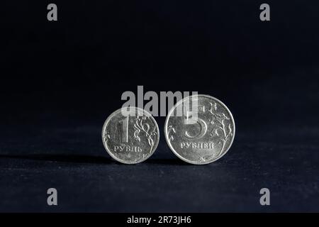 Picture of russian coins on a black background, with a focus on a coin of one ruble and five rubles. The ruble or rouble is the currency of the Russia Stock Photo
