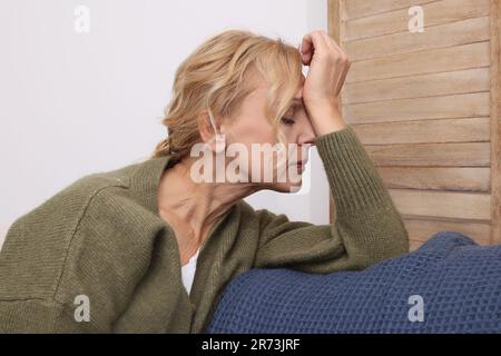 Upset middle aged woman sulking on sofa at home. Loneliness concept Stock Photo