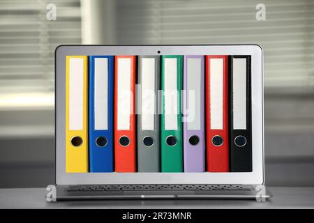 Store and organize information. Modern laptop with hardcover office folders on screen Stock Photo
