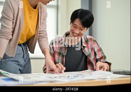 A handsome and smart young Asian male developer enjoys working and brainstorming on a new prototype for a new app with a female colleague in the offic Stock Photo