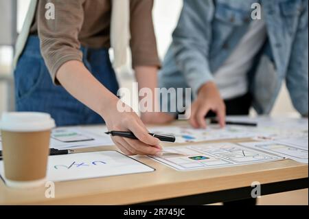 A close-up hand image of an app developer team is in the meeting, checking a new app prototype together. UI, UX, software, tech startup business Stock Photo
