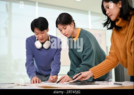 A beautiful and smart young Asian female graphic designer or app developer focuses on a new project, reviewing and analyzing a new app prototype with Stock Photo