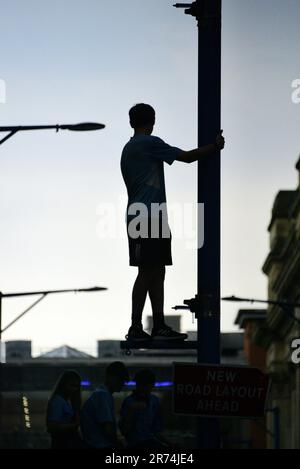 Manchester, UK. 12th June, 2023. A Man City fan stands on the strut on a street light to see the open top bus victory parade celebration in central Manchester, UK, to mark the achievement of their club winning the treble: the Premier League, the FA Cup, and the Champions League. On Saturday Man City beat Inter Milan in Istanbul to secure the Champions League win. The parade of open top buses went through Manchester city centre watched by large, enthusiastic crowds, despite a thunderstorm and heavy rain. Credit: Terry Waller/Alamy Live News Stock Photo