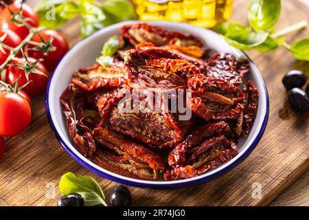 Sun-dried tomatoes marinated in olive oil with herbs and olives. Stock Photo