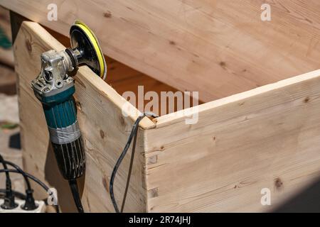 Wooden chest with old angle grinder during sunny day, closeup detail to power tool hanged on the board Stock Photo