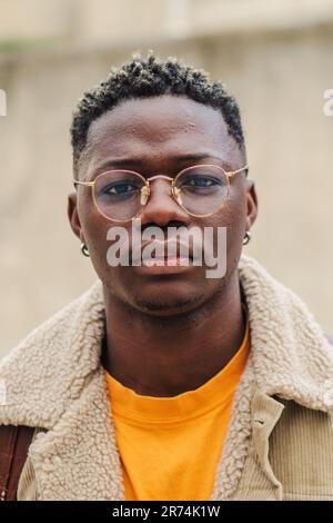 Vertical close up portrait of smart male teenager with googles at university campus. Young african american student looking serious at camera. Confident guy with pensive attitude. High quality photo Stock Photo