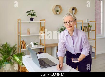 Senior business woman making notes in notebook while working or preparing for business meeting. Stock Photo