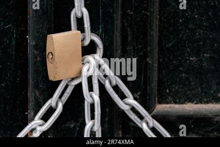 Metal padlock securing chains on an old wooden door Stock Photo
