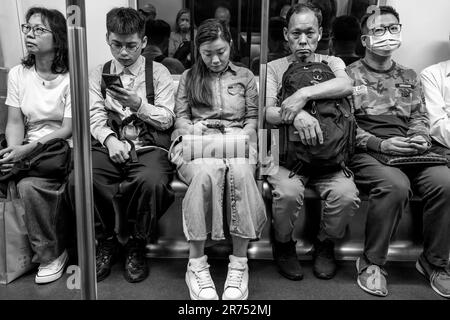 People Using Their Smartphones On A MTR Train, Hong Kong, China. Stock Photo