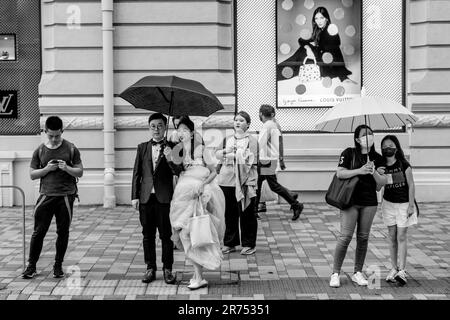A Just Married Couple Wait To Cross The Street, Kowloon, Hong Kong, China. Stock Photo